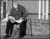 Man sitting on wall reading newspaper Rifford Road Exeter DSC02436.JPG