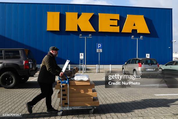 a-man-with-a-shopping-trolley-and-a-dog-passes-by-the-ikea-shop-in-krakow-poland-on-november.jpg